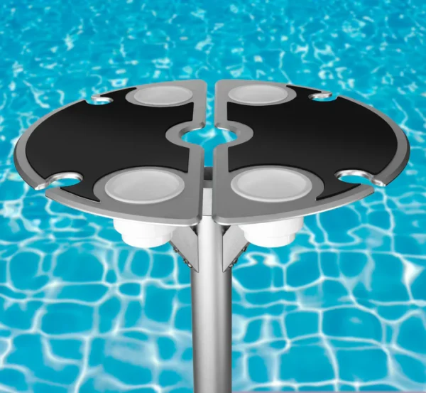Vibrant BajaMate silicone placemats in blue, red, and beige displayed on a 24" aluminum entertainment table, designed to reduce heat and protect surfaces, arranged neatly on a baja shelf with a sparkling pool in the background.