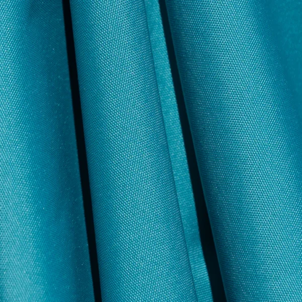 Close-up of a BajaMate Umbrella with a 2" silver aluminum pole and UV-resistant fabric in vibrant blue, showcasing its heavy-duty stainless steel crank mechanism and integrated 20-watt solar panel with a micro USB charging port for poolside use. The Teal umbrella