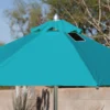 Close-up of a BajaMate Umbrella with a 2" silver aluminum pole and UV-resistant fabric in vibrant blue, showcasing its heavy-duty stainless steel crank mechanism and integrated 20-watt solar panel with a micro USB charging port for poolside use. The Teal umbrella